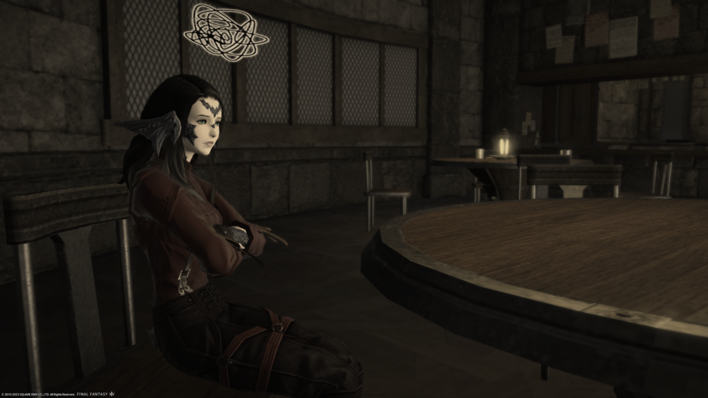 An FFXIV screenshot. An Au Ra is sitting alone at a table in a bar.